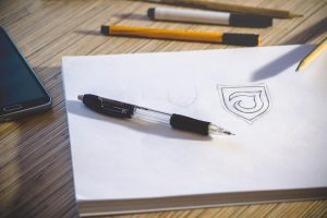 Sketching a shield design on paper