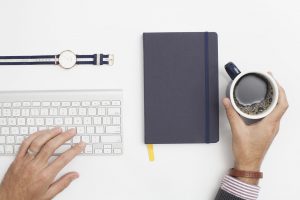 Coffee, notebook, keyboard, and watch.