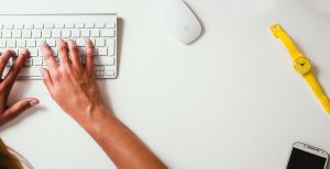 Hands typing on a keyboard, accessories.