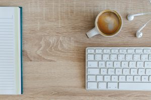 Desk with coffee, keyboard, and notebook